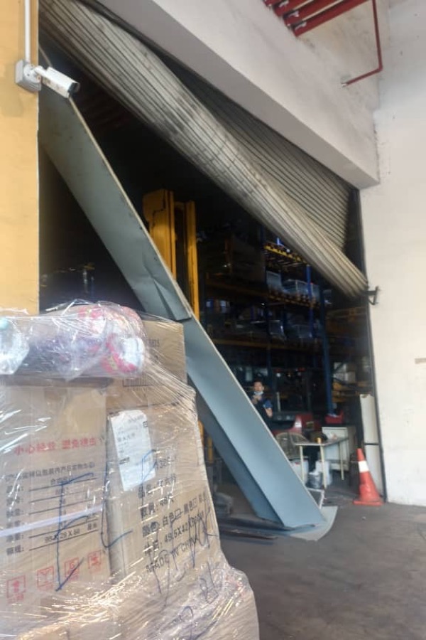 Damaged warehouse roller shutter requiring safety inspection