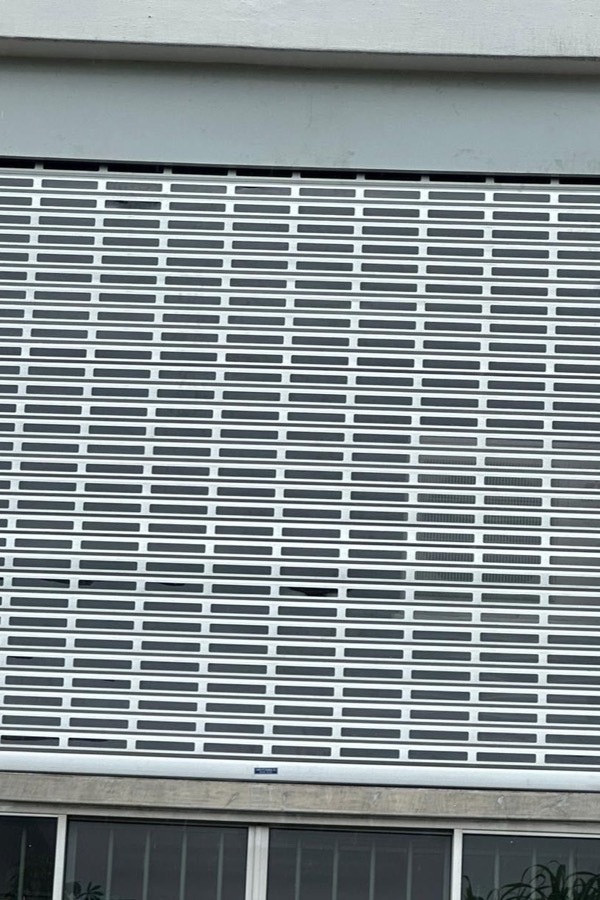 Perforated roller shutter installed over a window opening